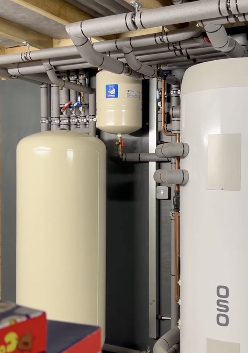 Hot water cylinder and buffer vessel with insulated pipework in a heat pump plant room